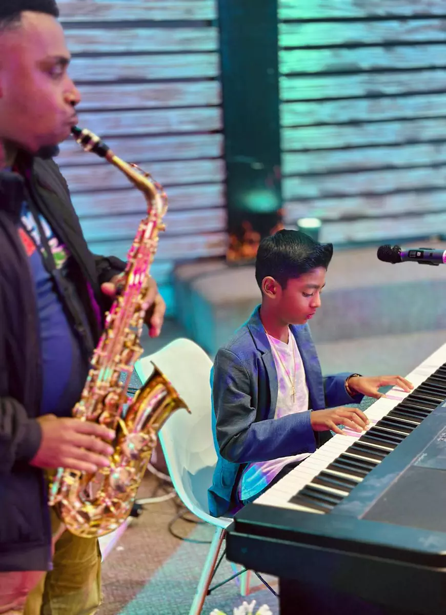 Man playing saxophone and a young boy playing keyboard on stage