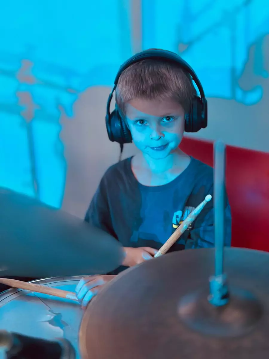 Young boy wearing headphones playing drums