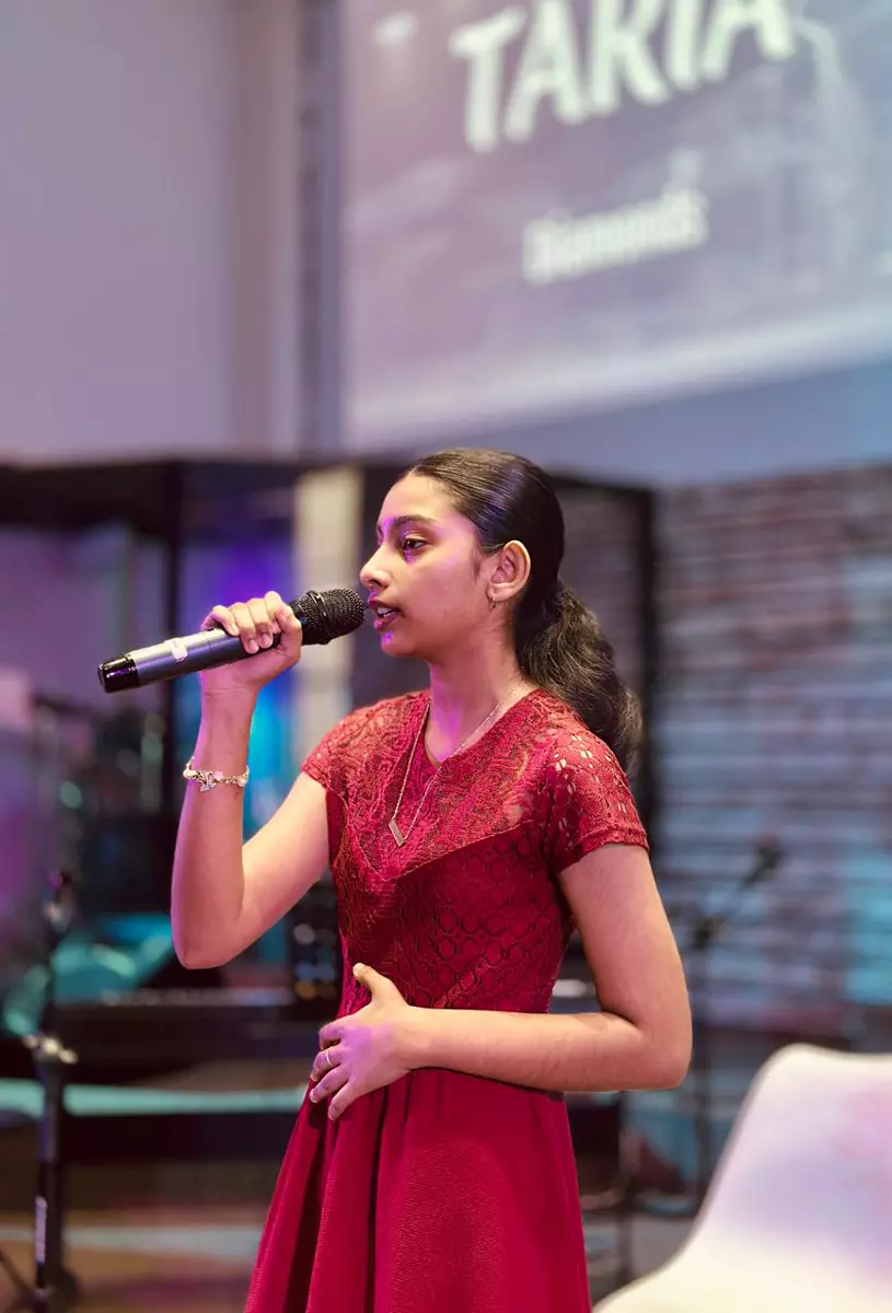 A young woman singing into a microphone on a stage