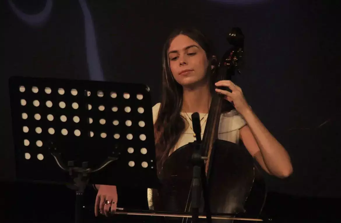 A young woman playing a cello behind a music stand
