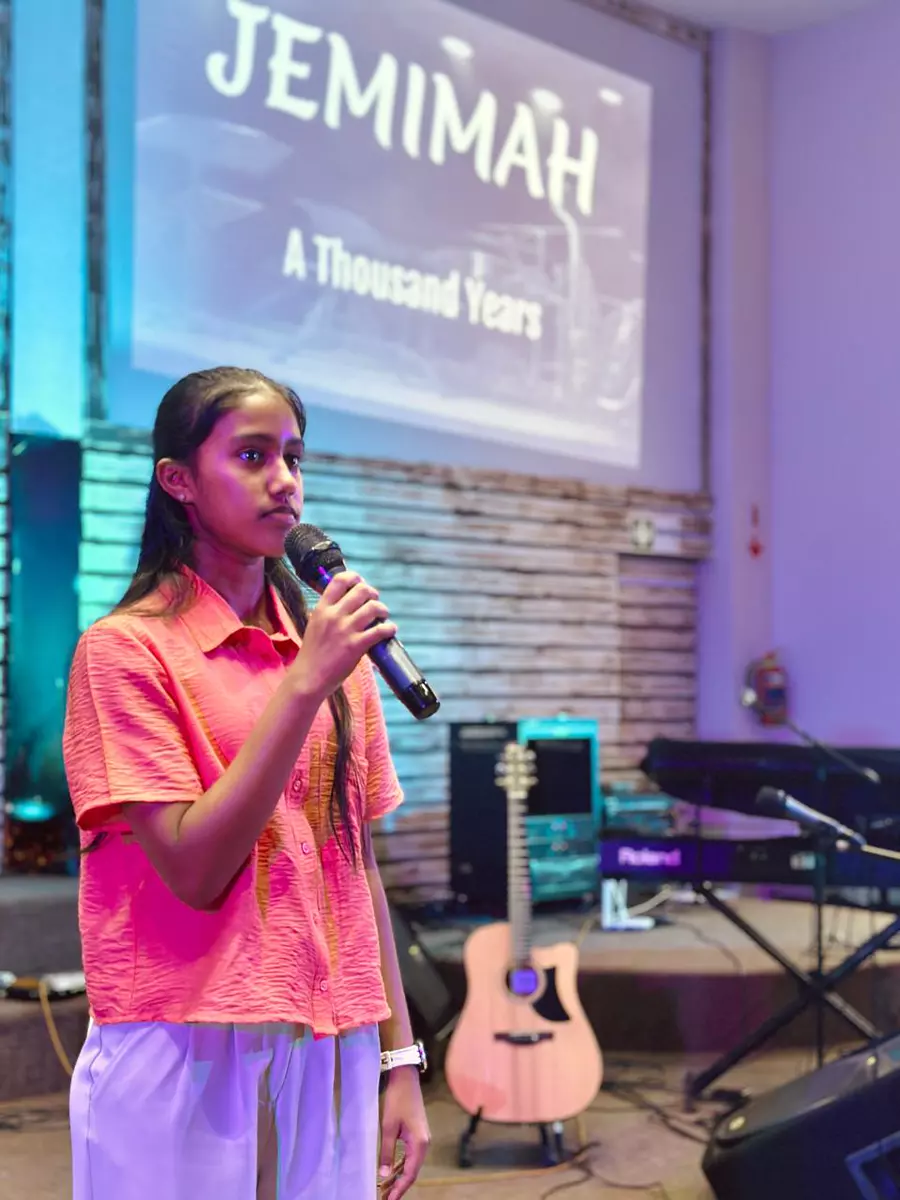 Young woman singing into a microphone on stage