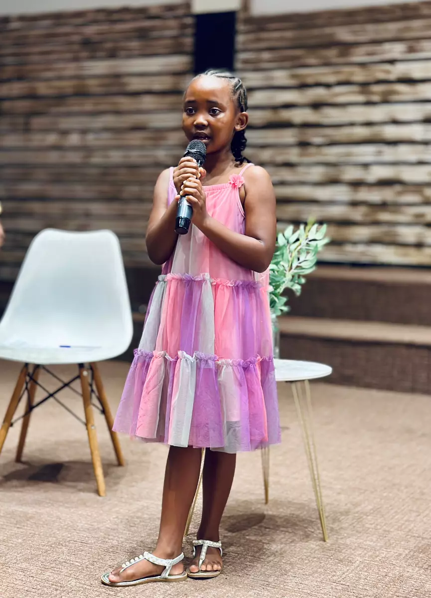 Young girl holding a microphone and speaking on stage